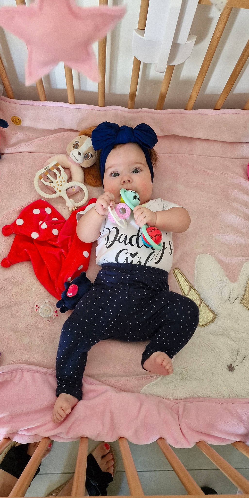 Aria a rejoint le concours — aidez-le/la à gagner de superbes lots ! baby_toddler_clothing, child, comfort, doll, fun, happy, hat, human_body, human_leg, lap, linens, pattern, person, pillow, pink, room, sitting, sleeve, thigh, toddler