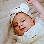 baby, infant, white_dress, headband, bow, soft_blanket, lying_down, cute, portrait, child, smiling, skin, face, arm, relaxed, indoors, young, toddler, clothing, person