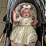 Esmée a rejoint le concours — aidez-le/la à gagner de superbes lots ! baby, infant, dress, headband, stroller, blanket, cushion, pattern, lace, smile, raised_arm, indoor, tile_floor, cute, person, child, comfortable, soft, pink, white