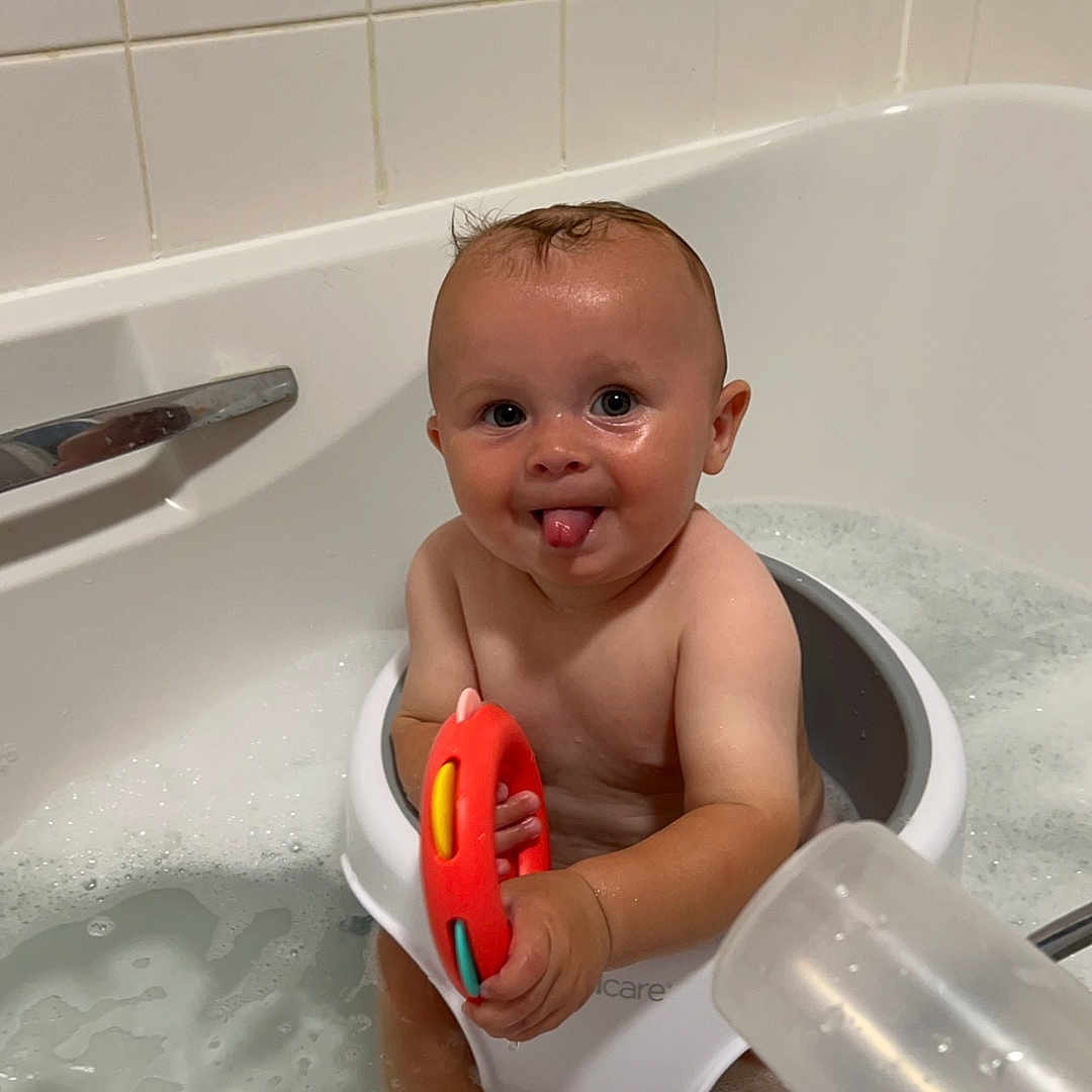 Jacob is registered to the contest to win money with this photo: baby, bathing, bathroom, bathtub, bodypart, bucket, face, finger, hand, head, indoors, mouth, person, photography, portrait, room, sitting, teeth, toilet, tub