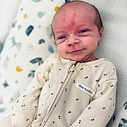 Harry is registered to the contest to win money with this photo: adorable, baby, child, clothing, cozy, cute, expression, face, head, indoor, infant, lying_down, newborn, onesie, pattern, pillow, skin, sleepwear, small, smile