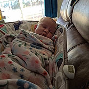 Tabitha is registered to the contest to win money with this photo: baby, baby_seat, blanket, child, couch, cozy, daylight, floral_pattern, home, indoor, infant, leather, nap, peaceful, portrait, resting, sleeping, soft, window, wrapped