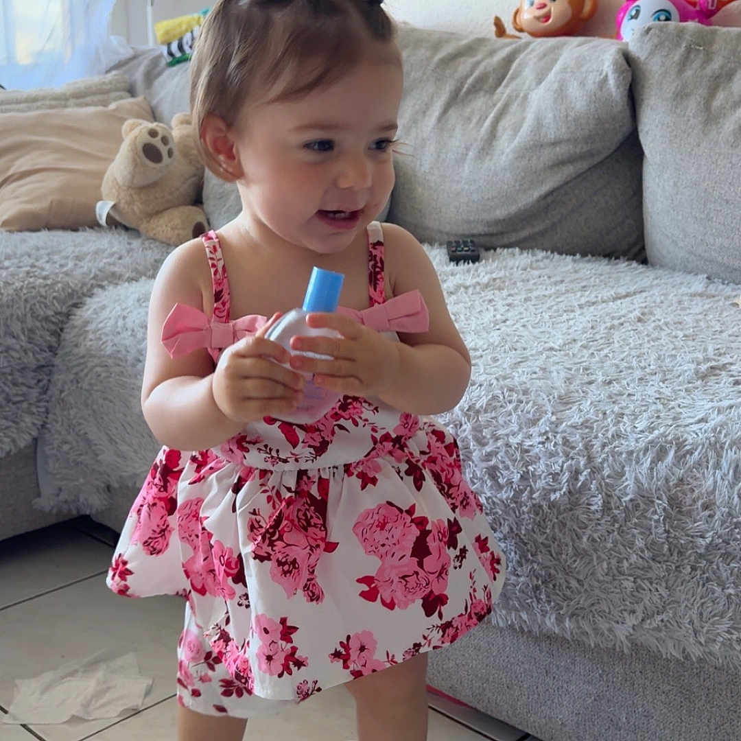 Lyhanna a rejoint le concours — aidez-le/la à gagner de superbes lots ! bottle, child, couch, curtain, dress, floor, floral, girl, happy, indoor, living_room, person, photo_frame, pigtails, smiling, sneakers, stuffed_toy, tile, toddler, window