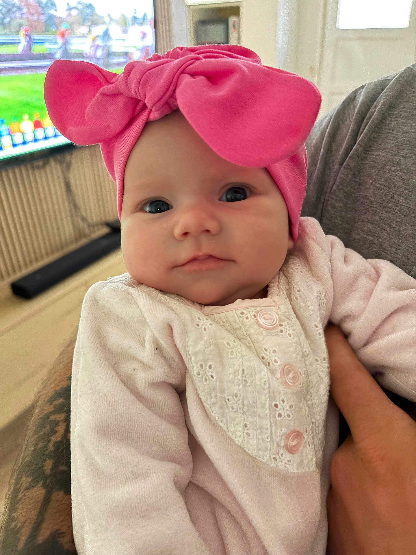 Lya a rejoint le concours — aidez-le/la à gagner de superbes lots ! baby, pink_bow, headband, infant, cute, close_up, portrait, indoors, tattoo, hand, white_outfit, clothing, soft, face, child, person, young, cute_expression, gaze, holding