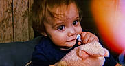 Amiyah is registered to the contest to win money with this photo: baby, big_eyes, blue_clothing, brown_hair, child, close_up, cozy, curious, cute, hand, indoor, nibbling, playing, plush_toy, portrait, smiling, soft_toy, toddler, warm_lighting, wooden_wall