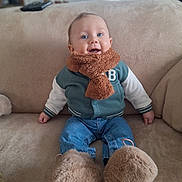 Ewen participe au concours pour gagner de l'argent avec cette photo : baby, child, smiling, scarf, jacket, blue_eyes, sitting, couch, remote_control, indoor, cozy, fluffy_slippers, jeans, happy, portrait, furniture, warm_clothing, cute, infant, home
