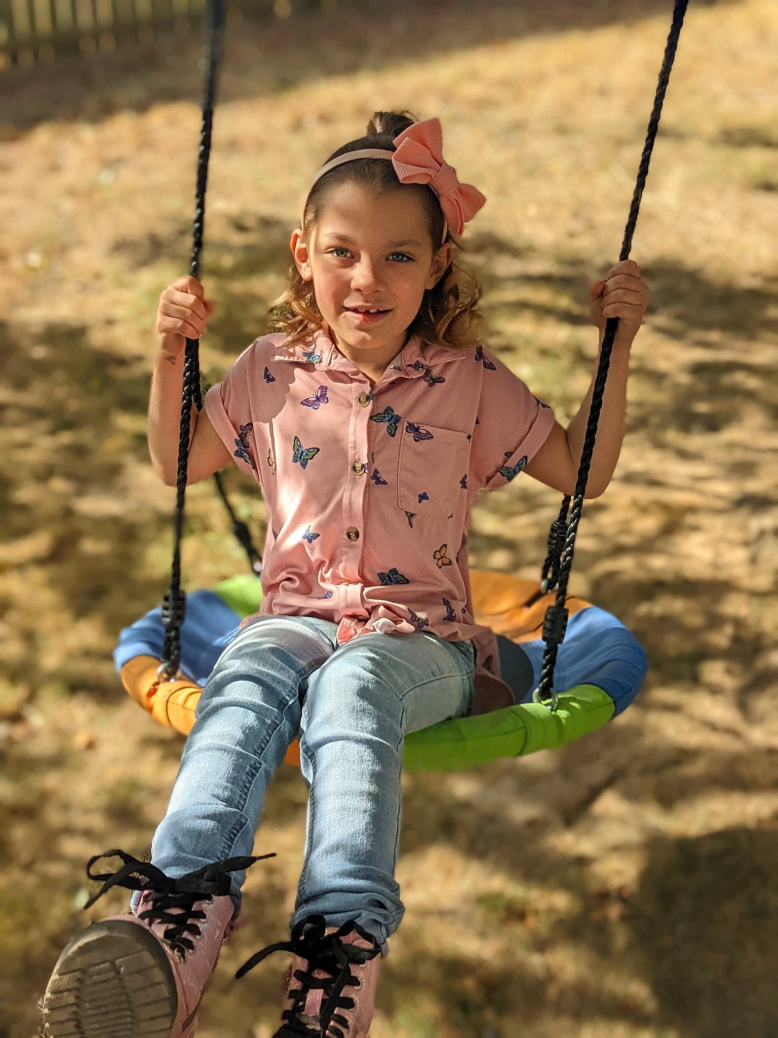 Layla is registered to the contest to win money with this photo: child, eye, face, fun, grass, happy, human, jeans, joy, leaf, leisure, outdoor_play_equipment, people_in_nature, person, playground, recreation, smile, swing, toddler, tree