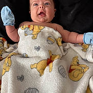 Alora is registered to the contest to win money with this photo: adorable, baby, blanket, child, comfort, cozy, cute, expression, face, head, indoor, infant, lying_down, mittens, portrait, skin, smiling, soft_texture, winnie_the_pooh, young