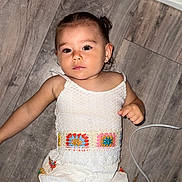 Djaïly a rejoint le concours — aidez-le/la à gagner de superbes lots ! baby, casual, child, clothing, colorful, crochet, cute, earrings, expression, floor, hand, head, home, indoor, looking_at_camera, person, sleeveless, toddler, white_outfit, wooden_floor