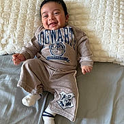 Ethan is registered to the contest to win money with this photo: baby, smiling, pajamas, bed, blanket, child, happy, clothing, person, cute, infant, soft, comfort, indoor, portrait, white, gray, cozy, socks, sleepwear