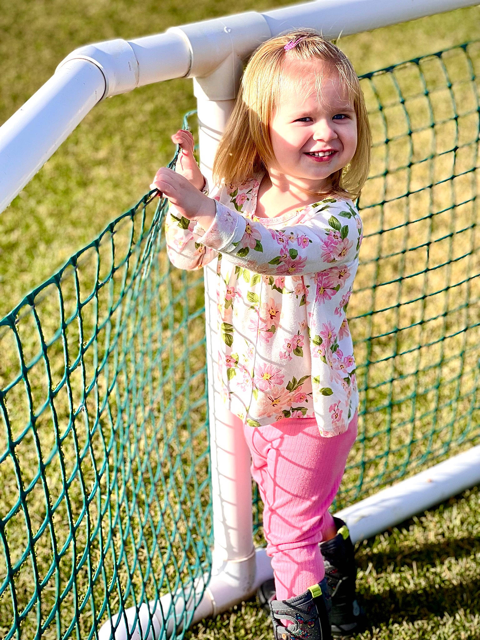 Charity is registered to the contest to win money with this photo: baby_toddler_clothing, blond, child, fun, grass, grass_family, happy, joy, leisure, mesh, outdoor_play_equipment, pattern, people_in_nature, person, photograph, plant, playground, recreation, sleeve, smile