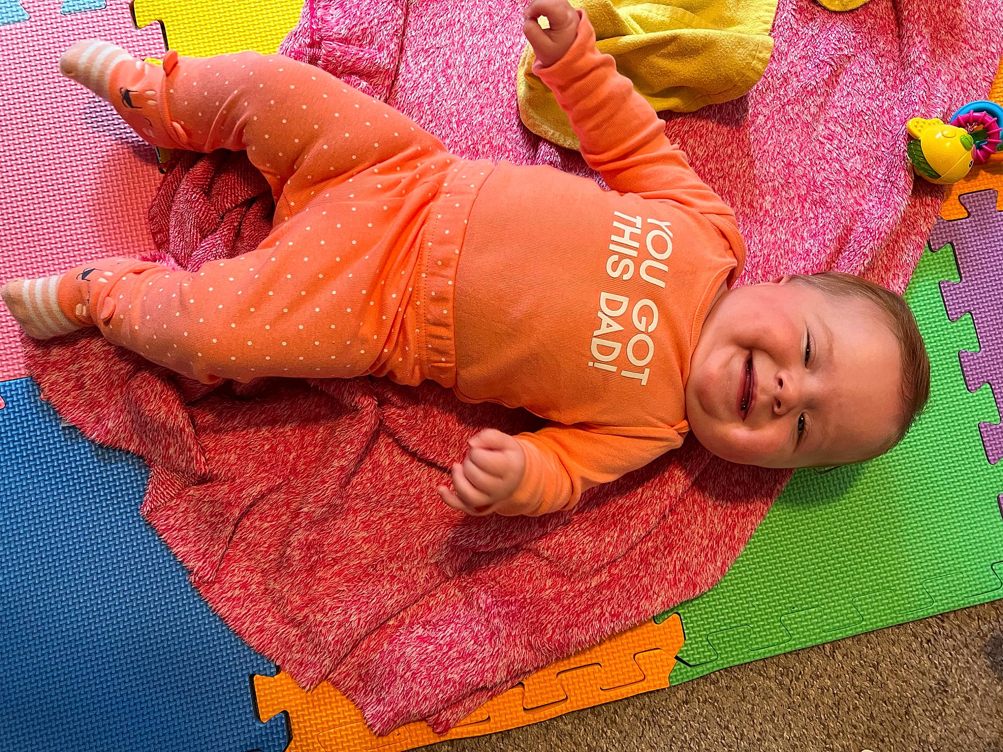 Hope is registered to the contest to win money with this photo: abdomen, baby, baby_toddler_clothing, comfort, finger, flooring, foot, human_body, human_leg, joy, leg, magenta, orange, pattern, person, pink, skin, sleeve, textile, toddler
