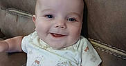 Wyatt is registered to the contest to win money with this photo: baby, child, infant, smiling, happy, portrait, sitting, armchair, furniture, indoor, close_up, face, eyes, mouth, short_hair, onesie, patterned_clothing, cushion, photography, adorable