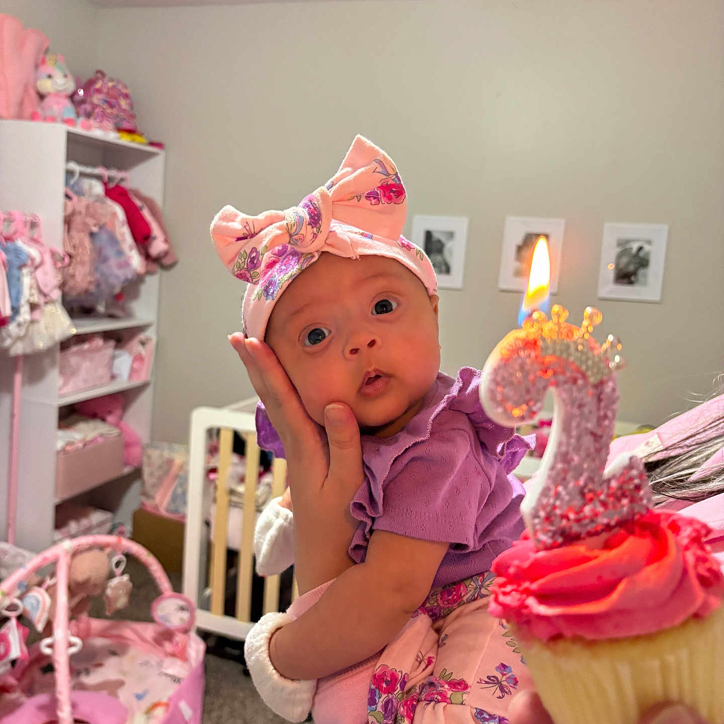 Kiylah joined the competition — help win amazing prizes! baby, child, birthday, cupcake, candle, pink, purple, headband, bow, surprised, hand, room, nursery, toys, clothing, person, celebration, indoors, carpet, furniture