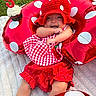 baby, child, birthday, cupcake, candle, red, polka_dot, hat, inflatable_ring, grass, blanket, smiling, cute, celebration, outdoor, happy, clothing, festive, food, person