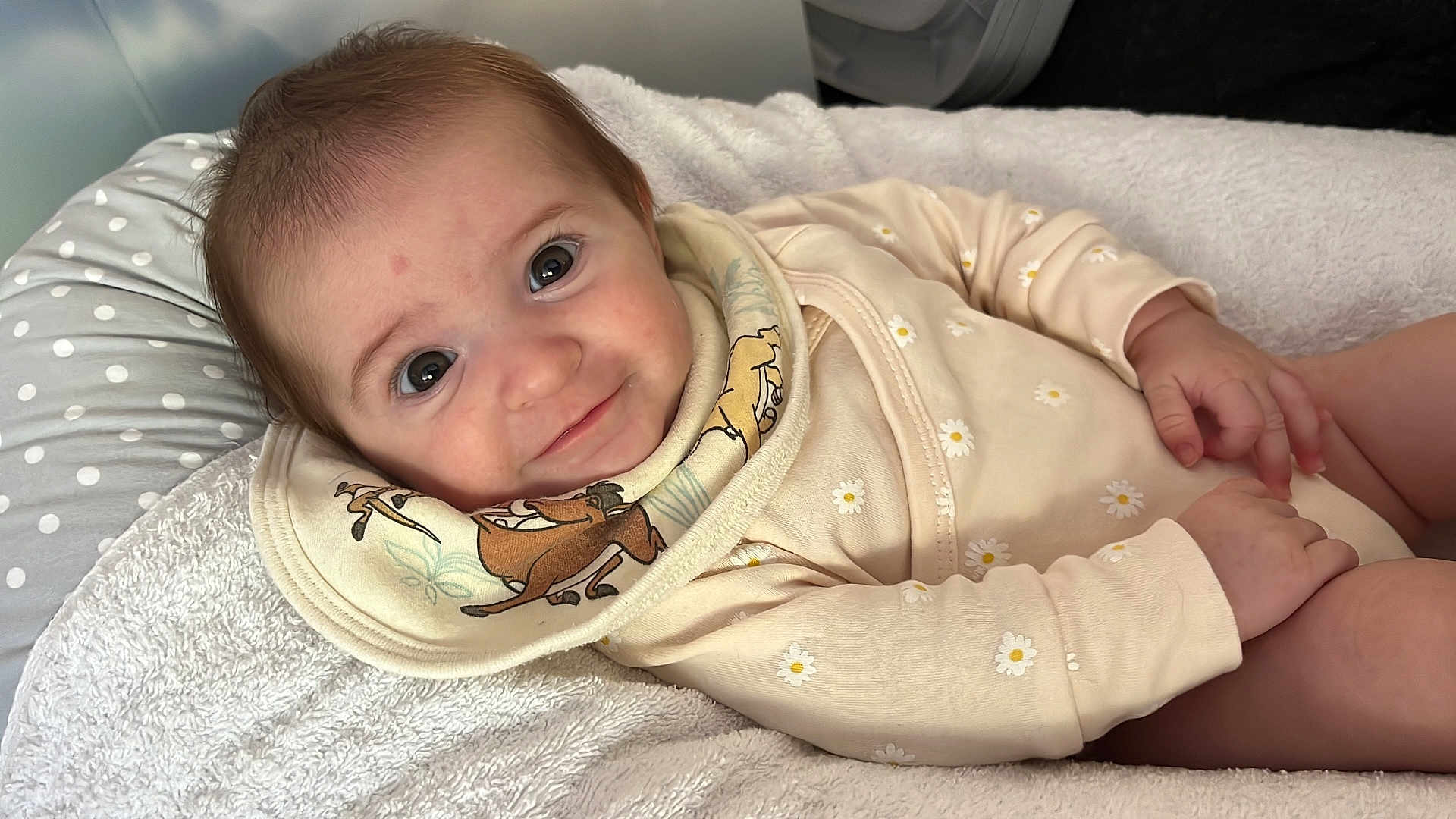 Alix participe au concours pour gagner de l'argent avec cette photo : baby, infant, smile, face, blanket, clothing, bib, cute, lying_down, soft_texture, patterned_clothes, cartoon, animal_print, hand, indoors, portrait, young_child, happy, skin, head