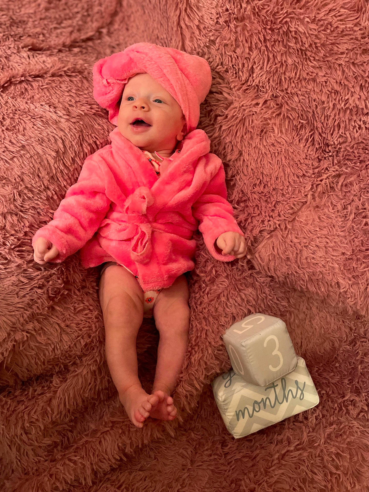Alaska is registered to the contest to win money with this photo: baby, baby_toddler_clothing, cheek, child, comfort, dress, fashion_accessory, flooring, fun, headwear, linens, magenta, pattern, peach, person, pink, sitting, skin, sleeve, smile