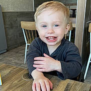 Kyler joined the competition — help win amazing prizes! child, toddler, smiling, blond_hair, blue_eyes, indoor, table, wood, chair, casual_clothing, happy, person, face, hand, cafe, background, furniture, light, portrait, cute
