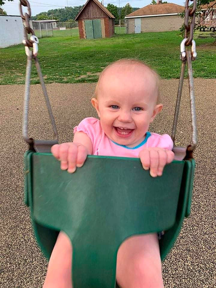 Katerina is registered to the contest to win money with this photo: baby, child, facial_expression, fun, grass, joy, outdoor_play_equipment, person, play, playground, public_space, smile, swing, toddler, vacation