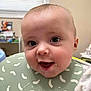Micah is registered to the contest to win money with this photo: baby, messy, bib, food, smiling, face, happy, indoor, child, head, clothing, person, highchair, feeding, room, window, sign, expression, cute, portrait