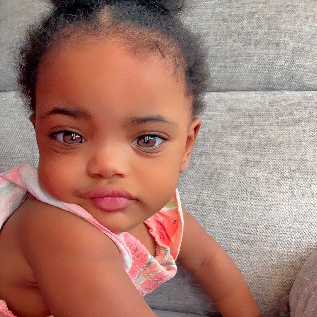 Chloe is registered to the contest to win money with this photo: toddler, child, baby, face, hair, couch, furniture, indoors, skin, arm, clothing, expression, cute, portrait, person, young_child, sitting, colorful, watermelon_pattern, curly_hair
