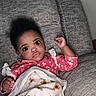 Chloe joined the competition — help win amazing prizes! baby, child, infant, blanket, sunflower, couch, gray_couch, pink_clothing, floral_pattern, wide_eyes, curious_expression, indoor, portrait, person, hand, cozy, resting, soft_texture, young_child, casual