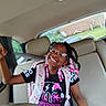child, girl, smiling, glasses, braids, beads, car, backseat, seatbelt, backpack, black_clothing, happy, portrait, indoors, seat, window, daylight, person, cute, joyful
