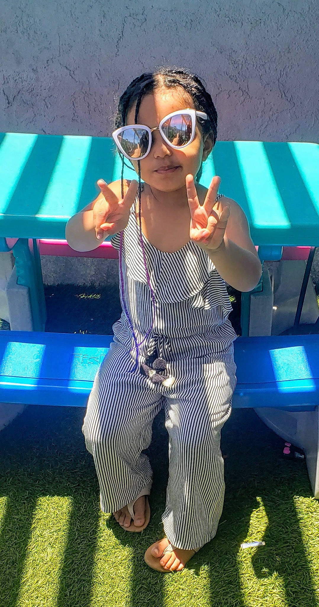 Maia is registered to the contest to win money with this photo: active_pants, baby_toddler_clothing, bracelet, cool, eyewear, gesture, glasses, goggles, hand, overall, person, sunglasses, thumb, vision_care