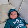 Issa participe au concours pour gagner de l'argent avec cette photo : baby, child, hoodie, smile, face, couch, pillow, clothing, indoor, person, happy, casual, sitting, young, cute, comfortable, portrait, infant, relaxing, teal