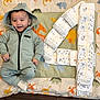 baby, child, hoodie, puma, quilt, dinosaur_pattern, diapers, number_four, smiling, lying_down, cute, clothing, footwear, socks, celebration, infant, indoor, floor, happy, portrait
