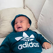 Issa a rejoint le concours — aidez-le/la à gagner de superbes lots ! baby, smiling, hoodie, adidas, couch, pillow, drool, happy, child, indoor, clothing, casual, young_child, portrait, person, relaxing, comfortable, cozy, sitting, cute