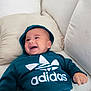baby, smiling, hoodie, adidas, couch, pillow, drool, happy, child, indoor, clothing, casual, young_child, portrait, person, relaxing, comfortable, cozy, sitting, cute