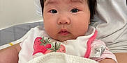 Isla is registered to the contest to win money with this photo: baby, child, infant, bib, blanket, person, face, hair, pink_clothing, white_clothing, indoor, cute, portrait, skin, young, chubby_cheeks, eyes, sitting, holding, soft_texture