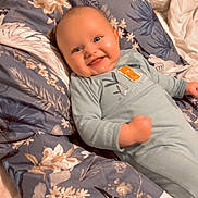 Ezio participe au concours pour gagner de l'argent avec cette photo : baby, smile, onesie, blanket, floral_pattern, bird_pattern, chubby_cheeks, happy, lying_down, indoors, child, infant, cute, face, blue_clothing, soft_lighting, portrait, cozy, joyful, human