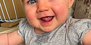 Athena joined the competition — help win amazing prizes! baby, blue_eyes, child, clothing, couch, cute, face, floral_pattern, grey_shirt, happy, indoor, infant, person, pink_design, portrait, short_hair, sitting, skin, smiling, toddler