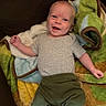 baby, smiling, infant, blanket, green_pants, gray_shirt, happy, lying_down, cute, face, child, young, cozy, soft_texture, indoors, person, close_up, portrait, bright_eyes, joyful