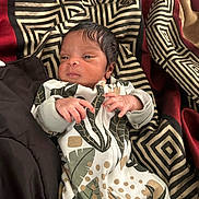 Dayton joined the competition — help win amazing prizes! baby, newborn, infant, blanket, patterned_clothing, leaf_pattern, geometric_pattern, fabric, hand, face, sleepwear, cozy, soft_lighting, portrait, person, cute, small, resting, indoors, child