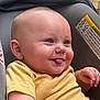 baby, child, tongue_out, yellow_shirt, car_seat, smiling, face, earring, skin, infant, cute, playful, comfort, seat, fabric, warning_label, closeup, head, expression, happy