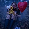 woman, dog, small_dog, raincoat, yellow_clothing, heart_balloon, balloon, forest, outdoors, autumn, fallen_leaves, sitting, portrait, smiling, long_hair, boots, fishnet_tights, dark_lighting, pet, romantic