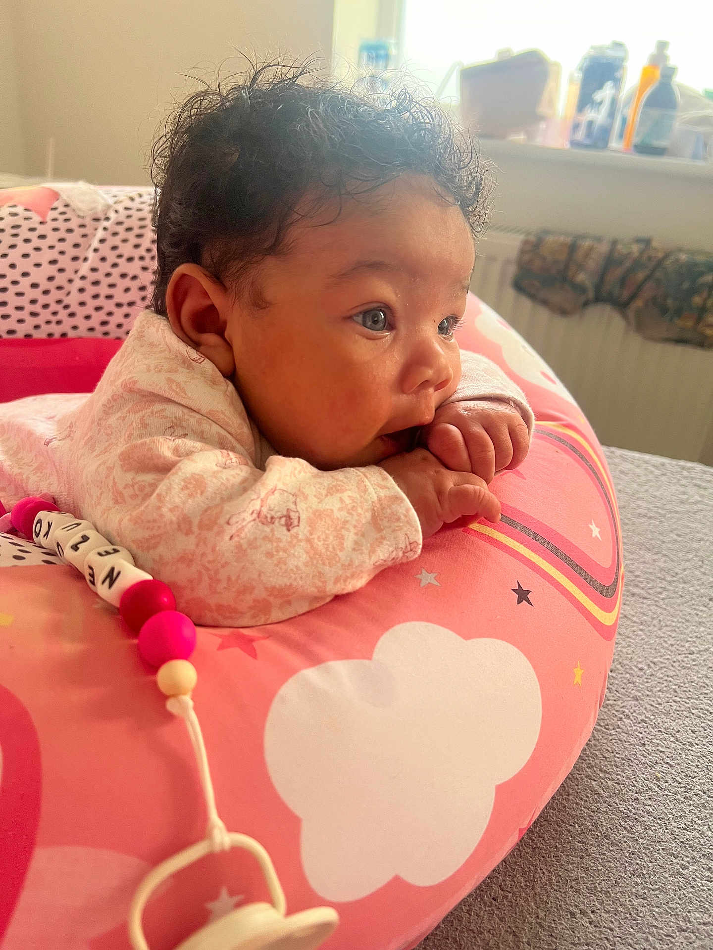 Nezuko joined the competition — help win amazing prizes! baby, infant, child, pink, cushion, cloud_pattern, hand, face, curly_hair, indoors, pacifier, toy, bedroom, soft_light, closeup, resting, cute, chewing, clothing, portrait