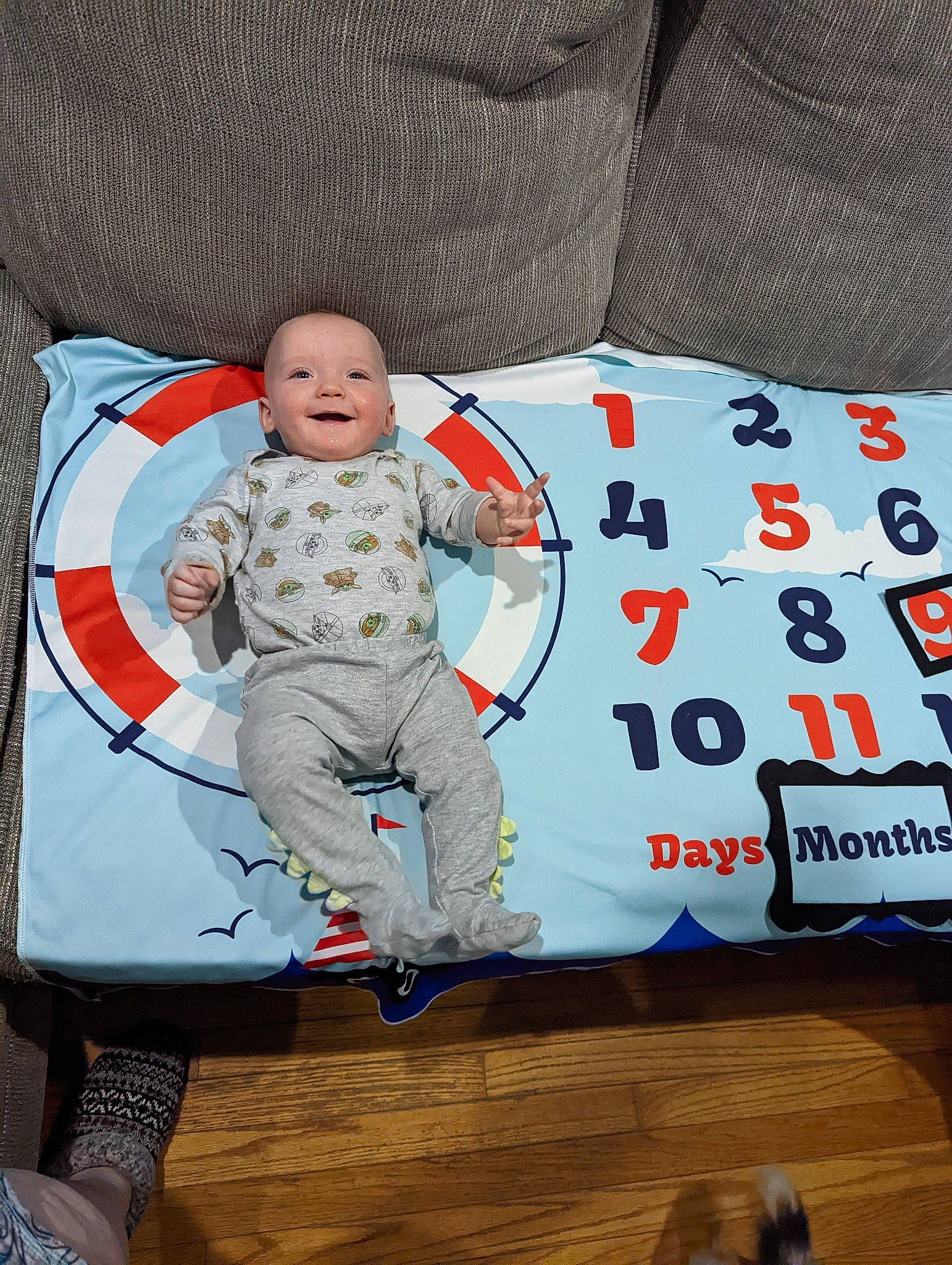 Alaric is registered to the contest to win money with this photo: baby, baby_products, baby_safety, baby_toddler_clothing, carmine, child, comfort, couch, flooring, hardwood, linens, pattern, person, room, sitting, sleeve, t_shirt, throw_pillow, toddler, wood
