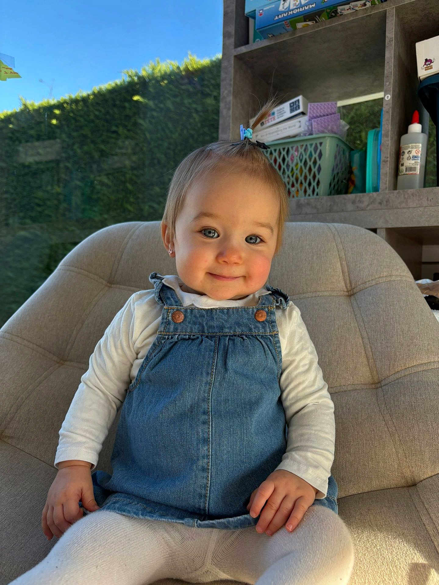 Lilou participe au concours pour gagner de l'argent avec cette photo : toddler, baby, child, denim_dress, white_shirt, tights, sitting, chair, smile, blue_eyes, hair_clip, rosy_cheeks, portrait, indoor, sunlight, shelves, storage_basket, toy_shelf, glue_bottle, happy