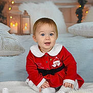 Lilou a rejoint le concours — aidez-le/la à gagner de superbes lots ! child, baby, infant, toddler, christmas, holiday, red_dress, festive, candles, lanterns, string_lights, blanket, pillow, portrait, sitting, smile, blue_eyes, indoor, cozy, soft_texture