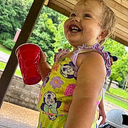 Myla joined the competition — help win amazing prizes! toddler, child, smiling, laughing, outdoor, portrait, red_cup, drinking_cup, summer, picnic, playground, wooden_shelter, trees, greenery, sunlight, colorful_dress, cartoon_pattern, stroller, park, happy