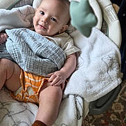 Dalton joined the competition — help win amazing prizes! baby, child, infant, smiling, portrait, indoor, rocker, blanket, toy, baby_clothing, orange_outfit, brown_sock, seated, lying_down, face, eyes, home, furniture, soft_blanket, carpet