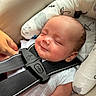 baby, car_seat, sleeping, harness, infant, child, cushion, headrest, hand, white_clothing, smile, closeup, indoor, safe, comfort, seatbelt, resting, peaceful, cute, newborn