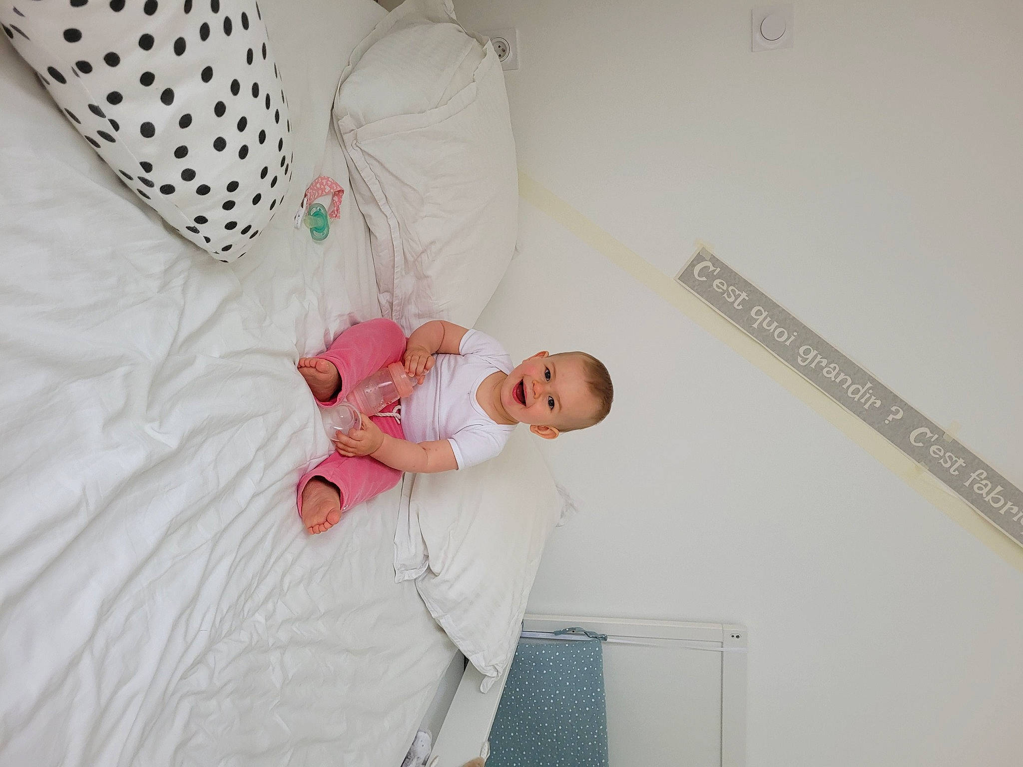 Manon participe au concours pour gagner de l'argent avec cette photo : baby, baby_products, baby_safety, baby_toddler_clothing, bed, bed_sheet, bedding, bedroom, child, comfort, happy, joy, linens, magenta, pattern, person, room, sitting, sleeve, t_shirt