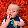 Myles joined the competition — help win amazing prizes! baby, infant, smiling, blue_eyes, bib, dinosaur, adorable, hand, orange_blanket, fluffy, cute, lying_down, clothing, child, happy, face, skin, person, toddler, playful