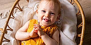 Elio a rejoint le concours — aidez-le/la à gagner de superbes lots ! baby, child, smiling, tongue_out, wicker_basket, yellow_clothing, white_fabric, indoor, cute, portrait, infant, happy, baby_clothes, wood_floor, hands, face, person, closeup, light, playful