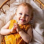 baby, child, smiling, tongue_out, wicker_basket, yellow_clothing, white_fabric, indoor, cute, portrait, infant, happy, baby_clothes, wood_floor, hands, face, person, closeup, light, playful